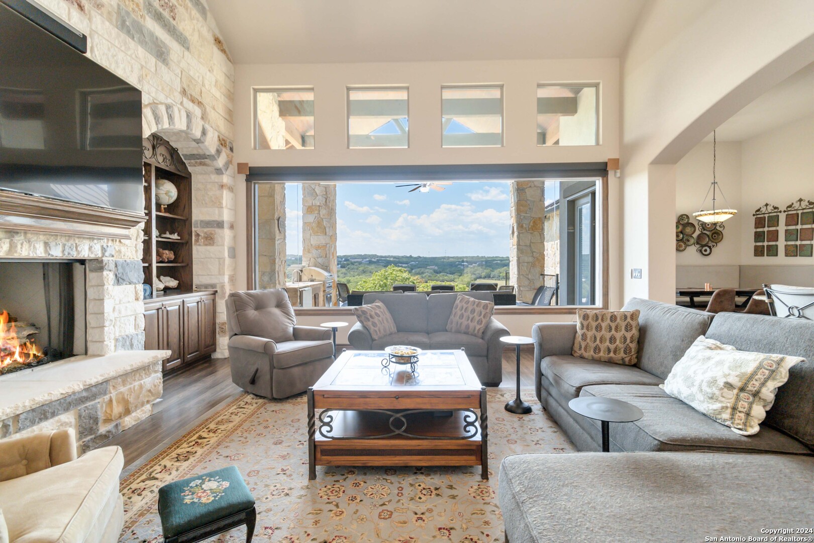 a living room with furniture large windows a fireplace and a flat screen tv