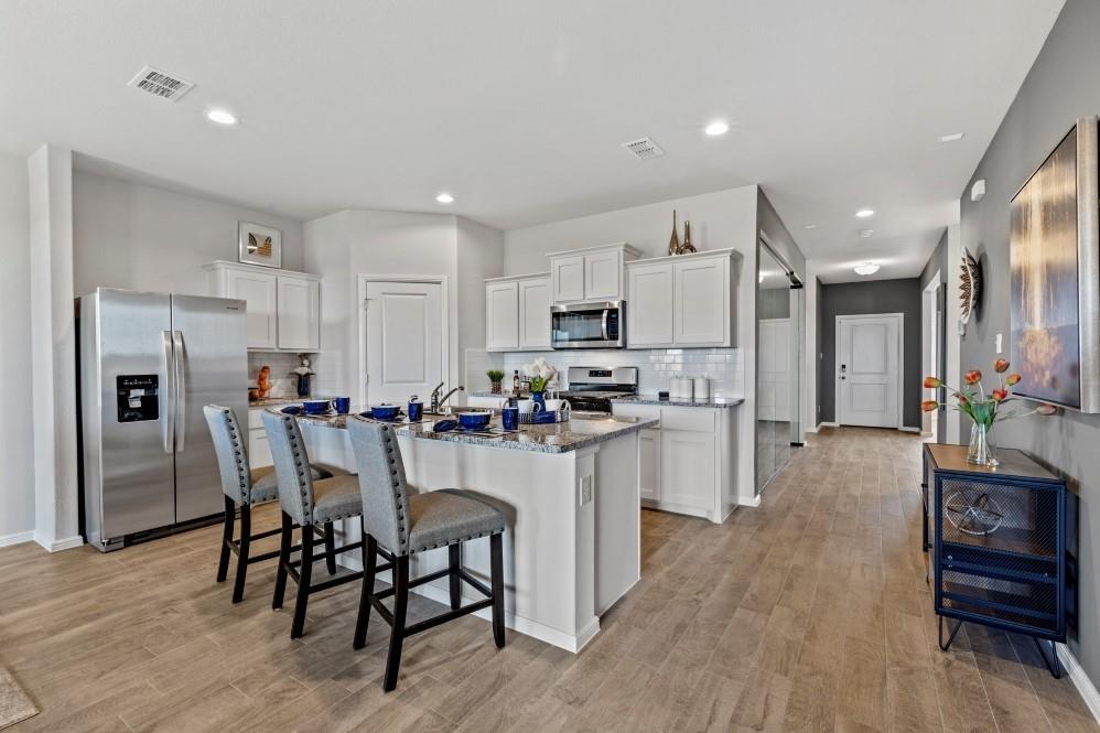 a kitchen with refrigerator a stove a dining table and chairs