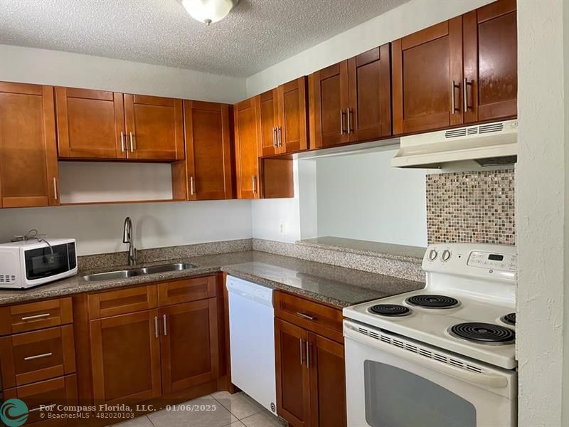 a kitchen with granite countertop a sink stove and cabinets