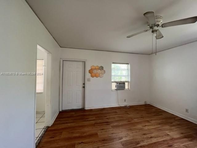 an empty room with wooden floor chandelier fan and windows