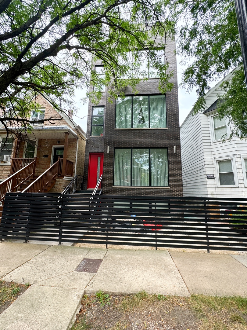 a view of brick house with large windows and a large tree