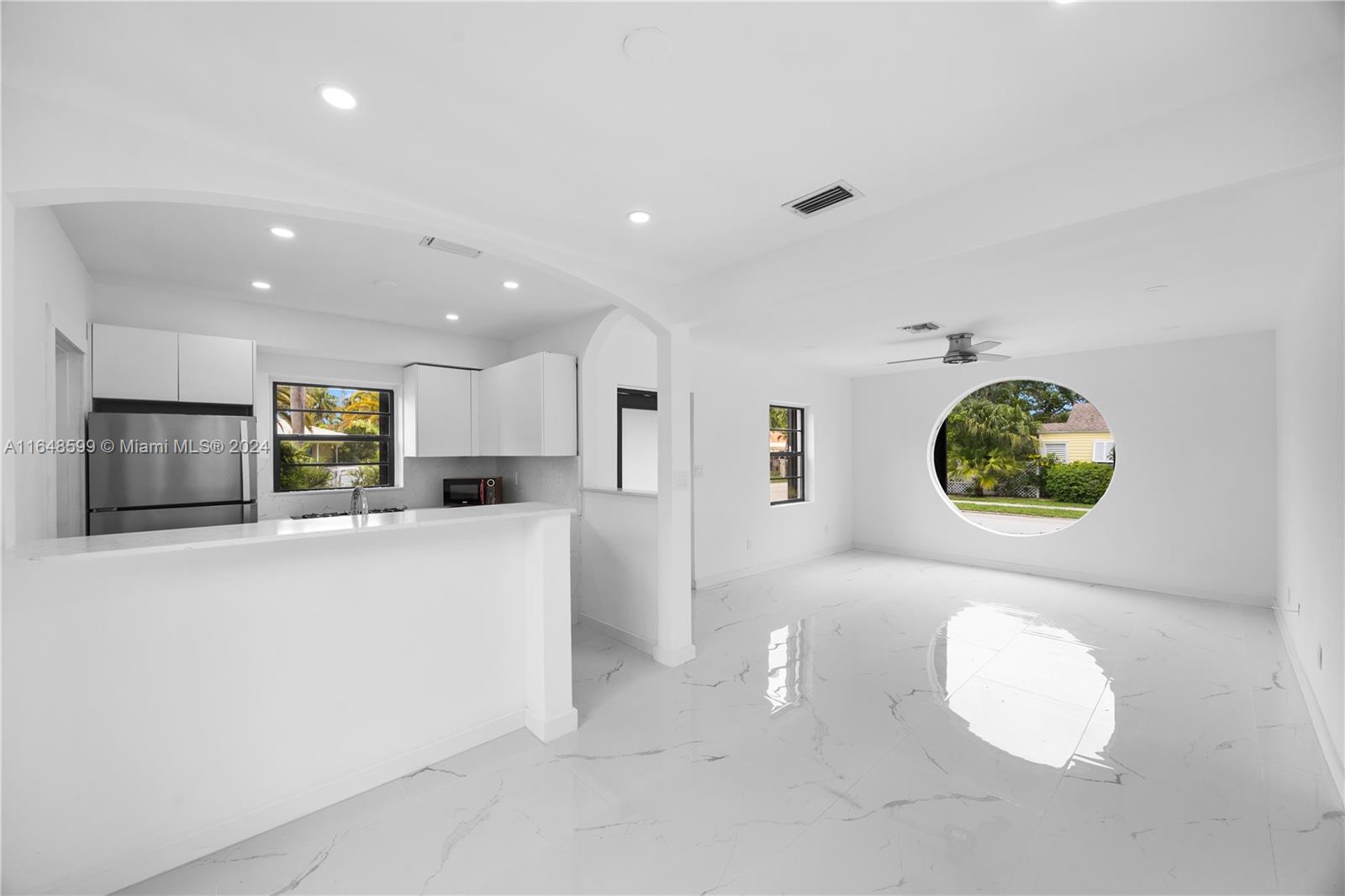 a view of kitchen with stainless steel appliances granite countertop a refrigerator a stove and a dining table with wooden floor