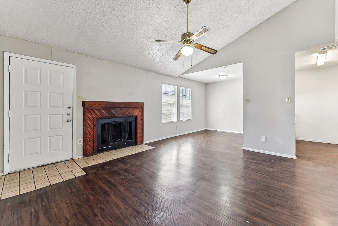 a view of an empty room with wooden floor fireplace and a window