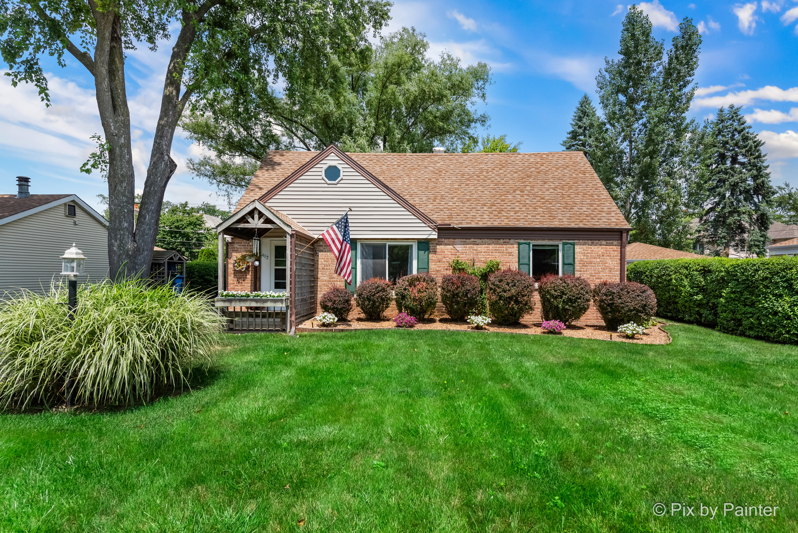 a front view of a house with a garden and trees