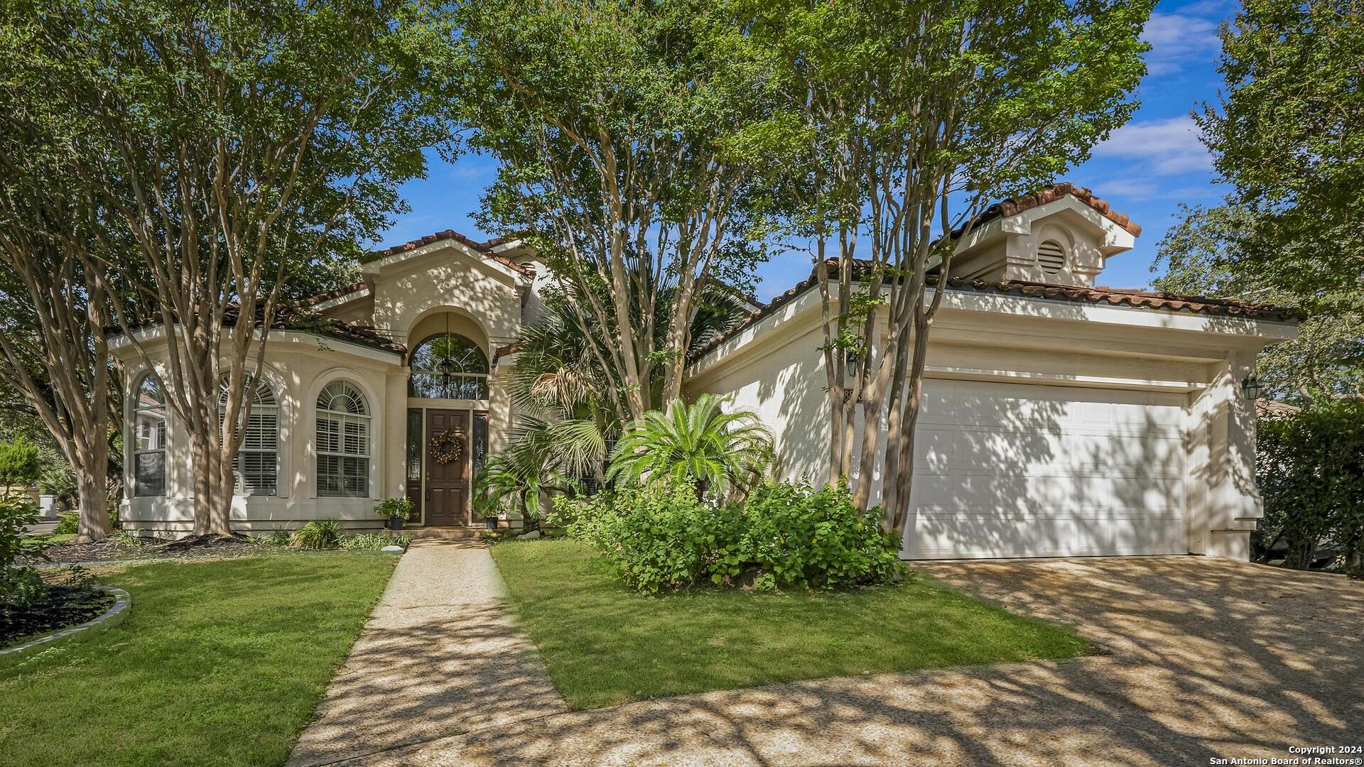 a front view of a house with a garden and trees