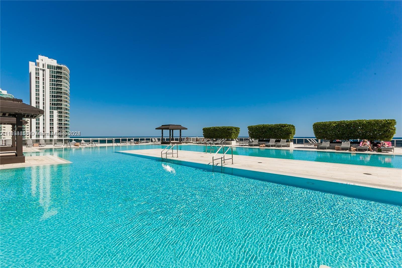 a view of swimming pool with lawn chairs and wooden fence