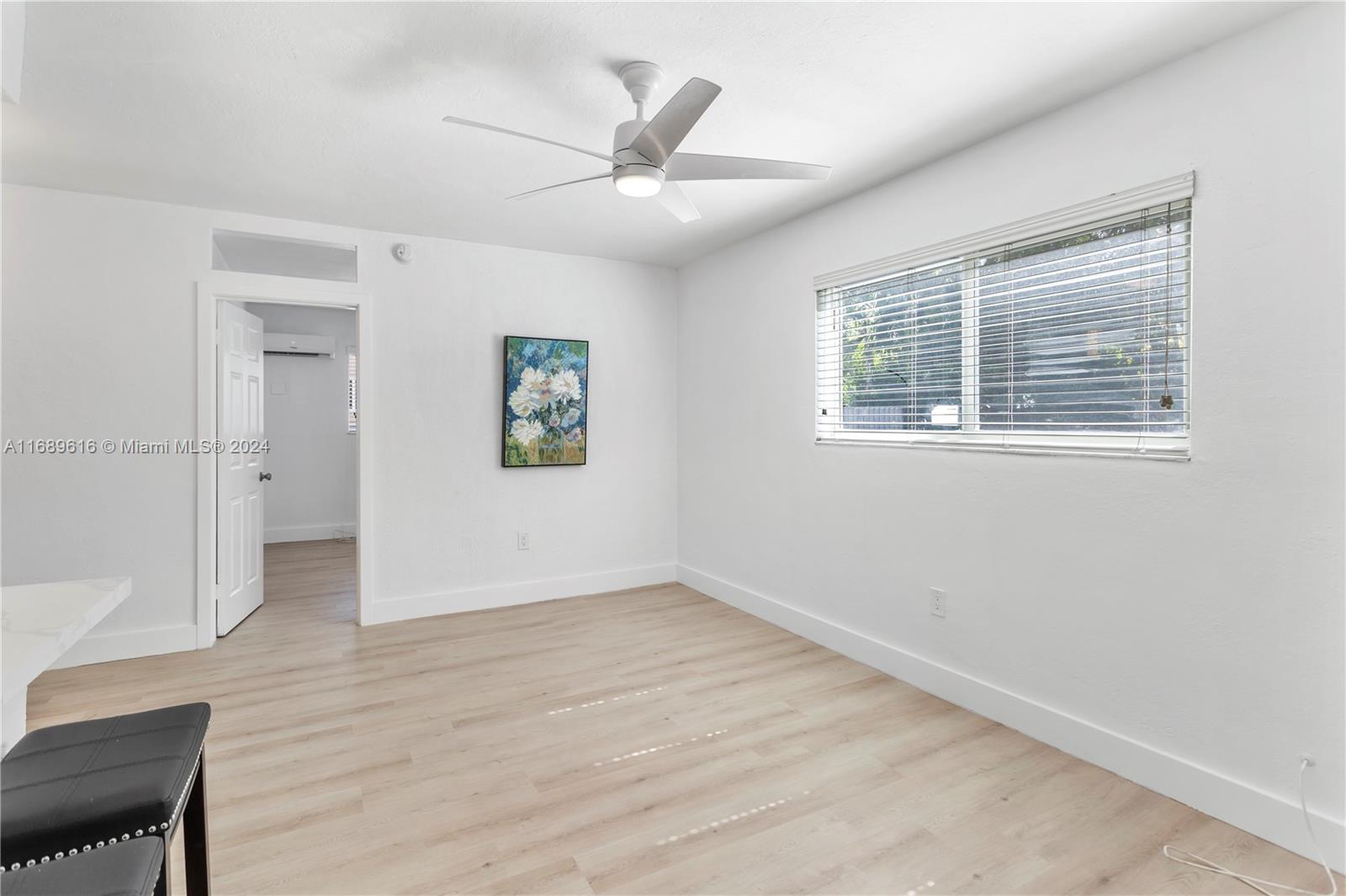 an empty room with wooden floor a ceiling fan and windows