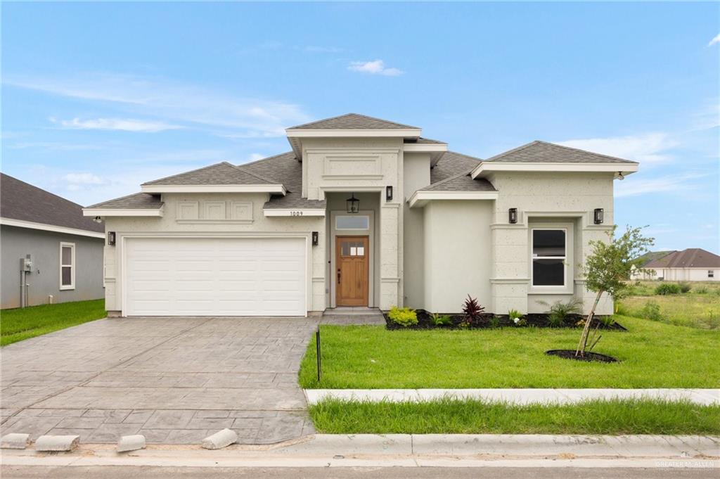 Prairie-style home featuring a garage and a front lawn