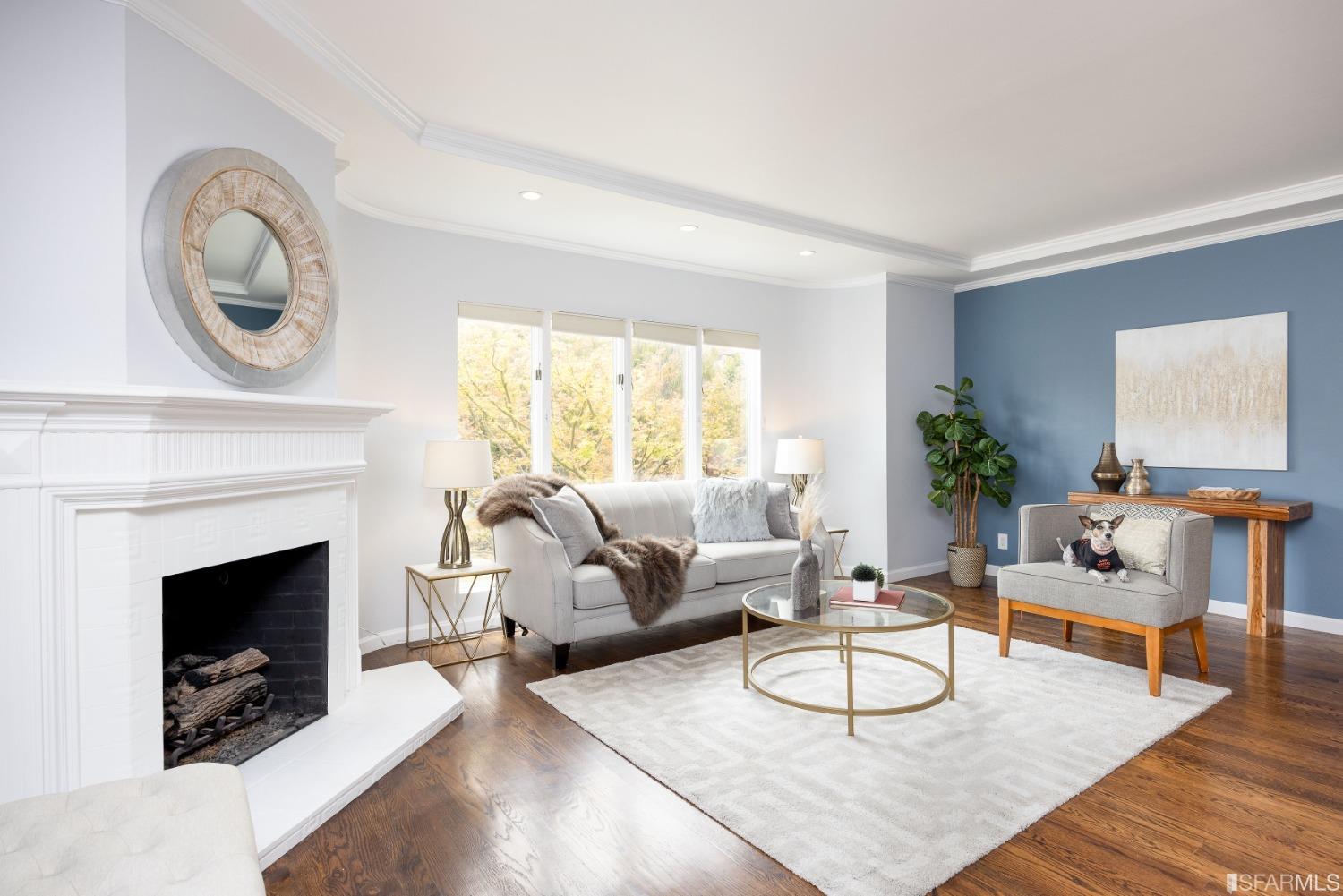 a living room with furniture a rug a fireplace and a large window