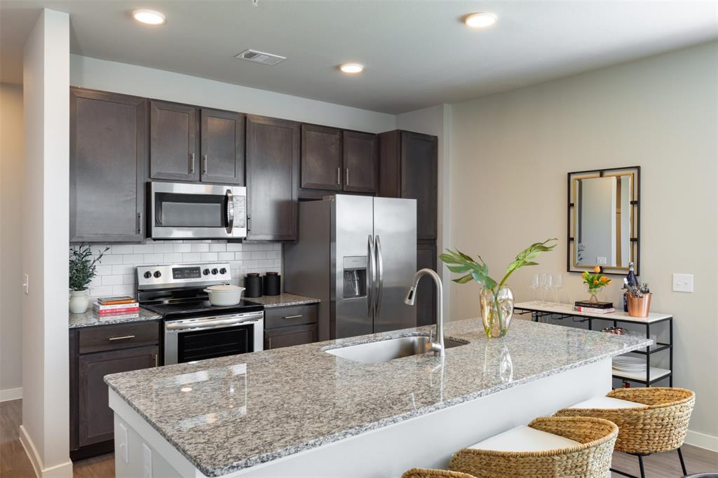 a kitchen with stainless steel appliances granite countertop a sink refrigerator and microwave