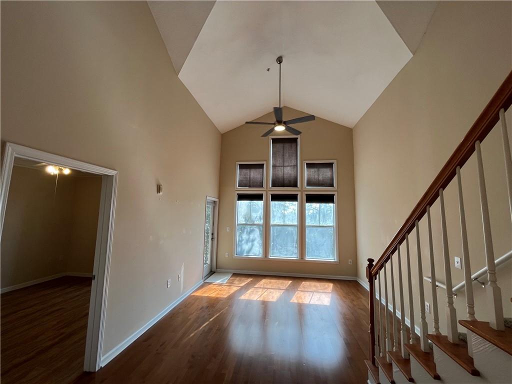 a view of an empty room with wooden floor and stairs