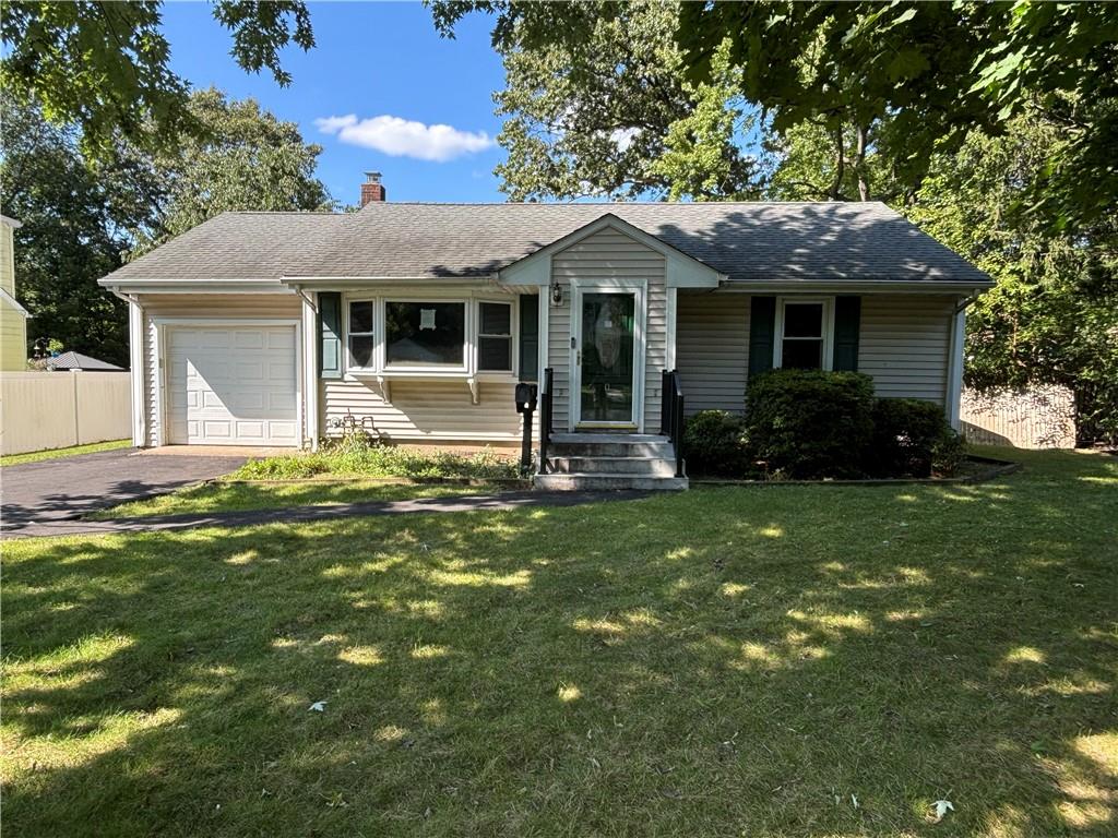 Single story home with a garage and a front lawn