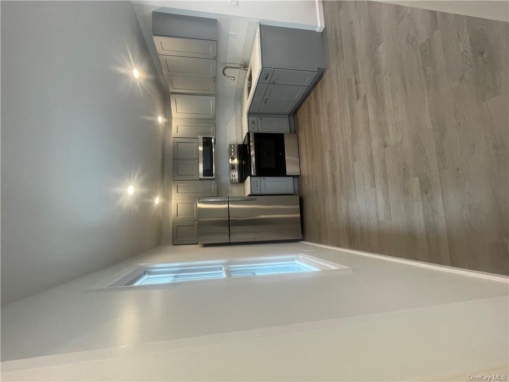 Kitchen featuring gray cabinets, stainless steel appliances, light wood-type flooring, and sink