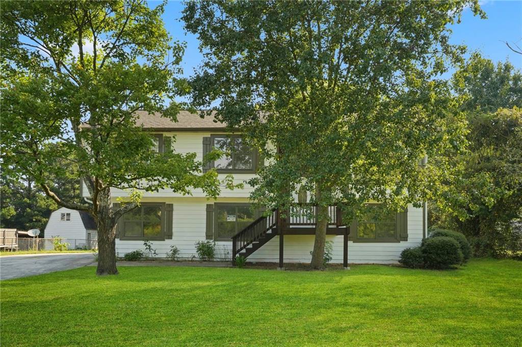 a view of a house with a big yard and large trees