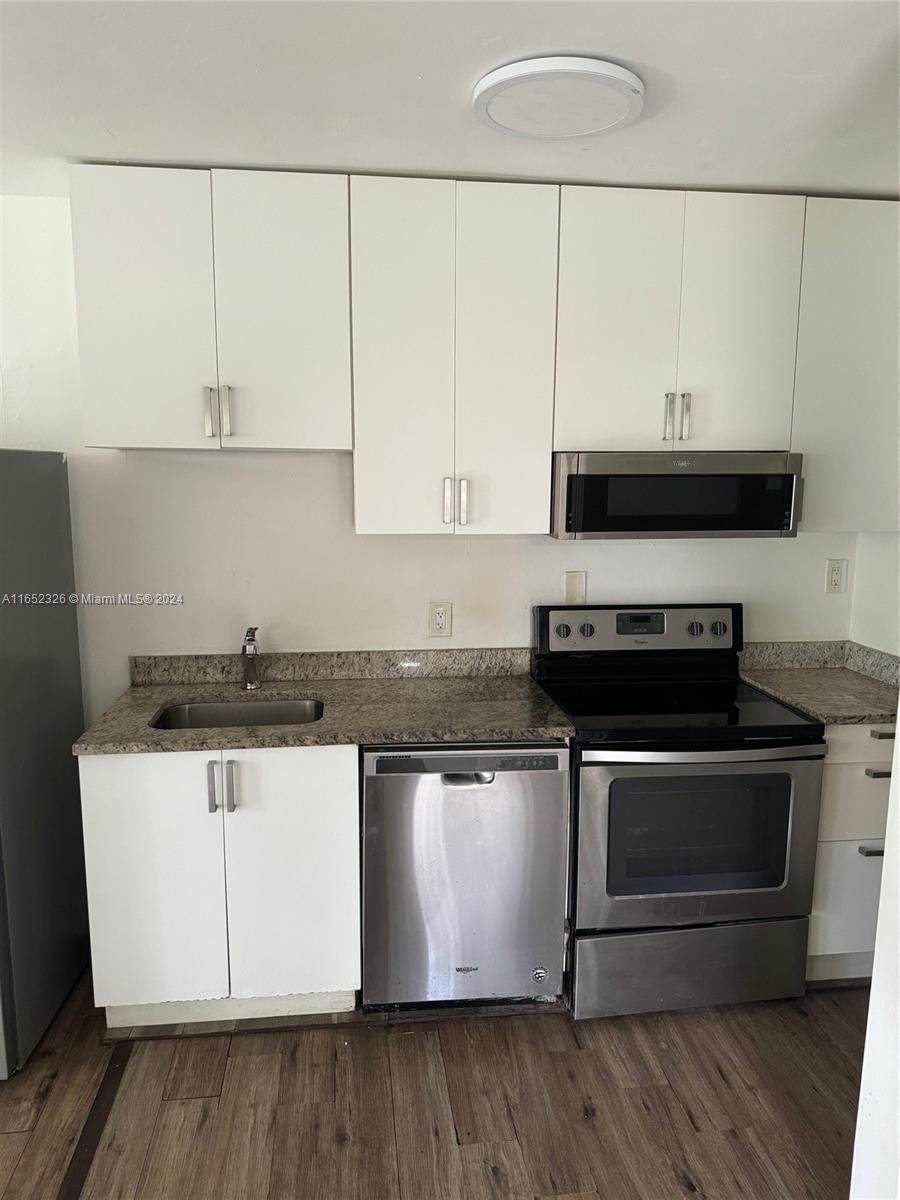 a kitchen with stainless steel appliances a stove a microwave and white cabinets