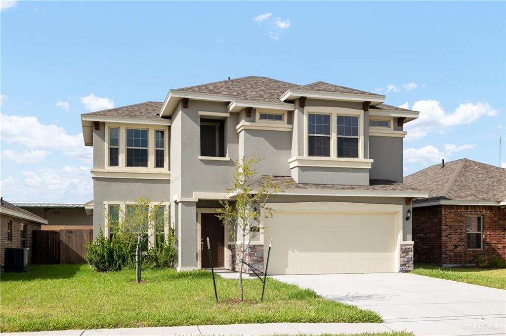 Prairie-style home featuring central AC unit, a garage, and a front lawn