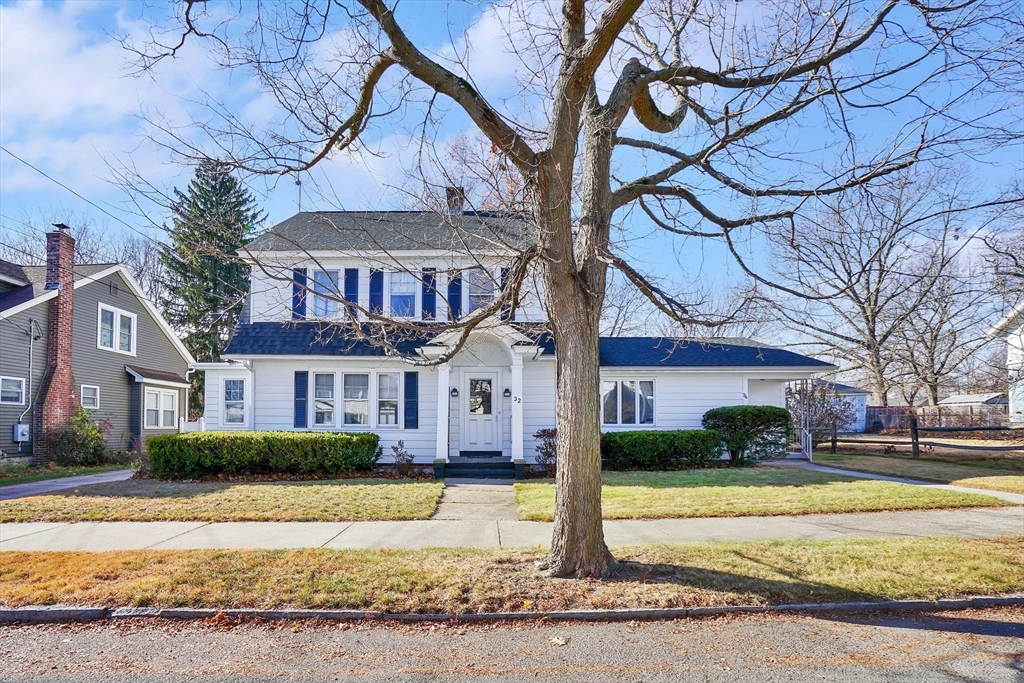 a front view of a house with a yard with plants and trees