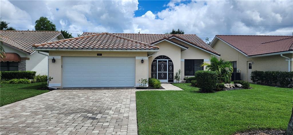 Mediterranean / spanish home with a garage, central AC unit, and a front lawn