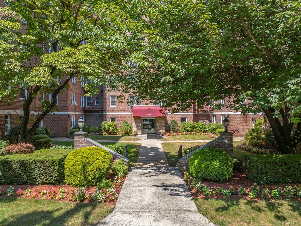 a front view of a house with fountain and large trees