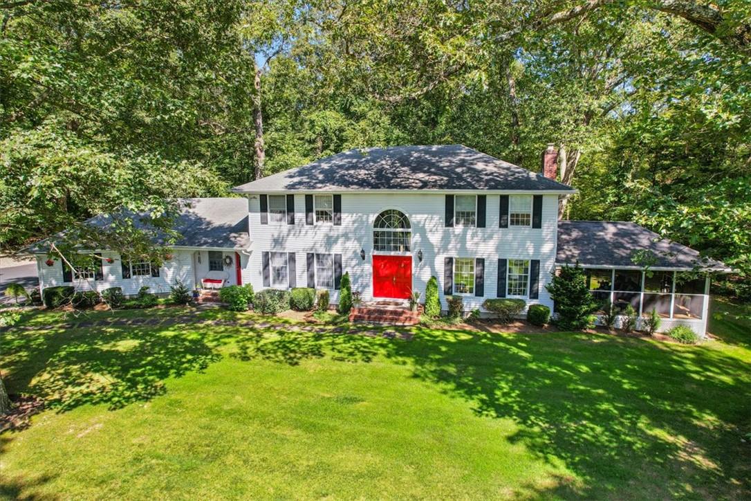 Colonial home featuring a sunroom and a front yard