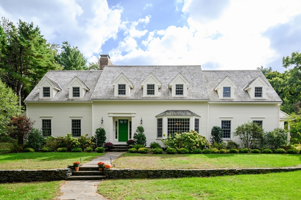 a front view of a house with a garden and trees