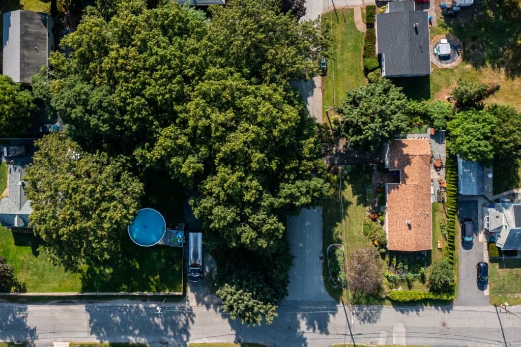 an aerial view of residential house with outdoor space and trees all around