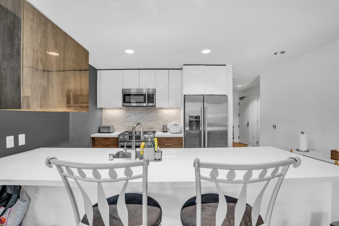 a kitchen with stainless steel appliances kitchen island granite countertop a dining table chairs and refrigerator