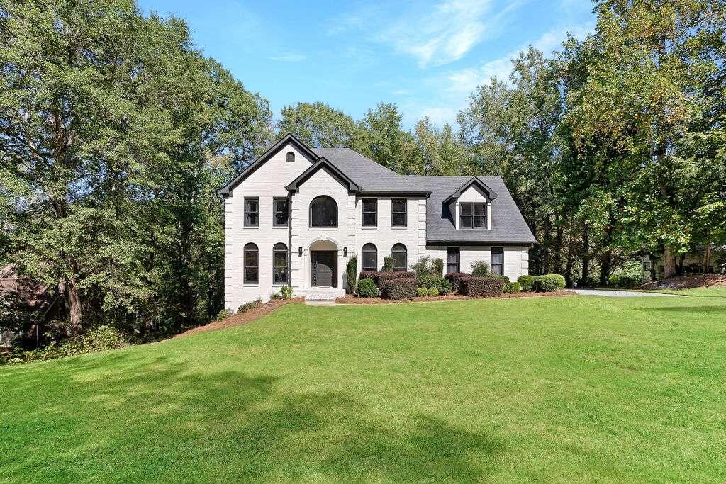 a view of a house with a big yard and large trees