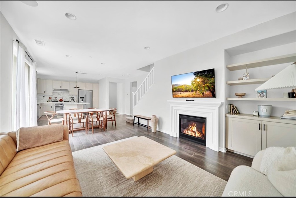 a living room with furniture a fireplace a flat screen tv and kitchen view