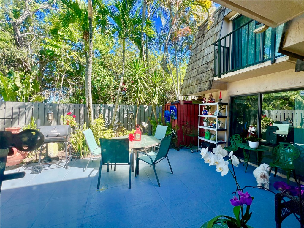 a view of a patio with table and chairs potted plants and large tree