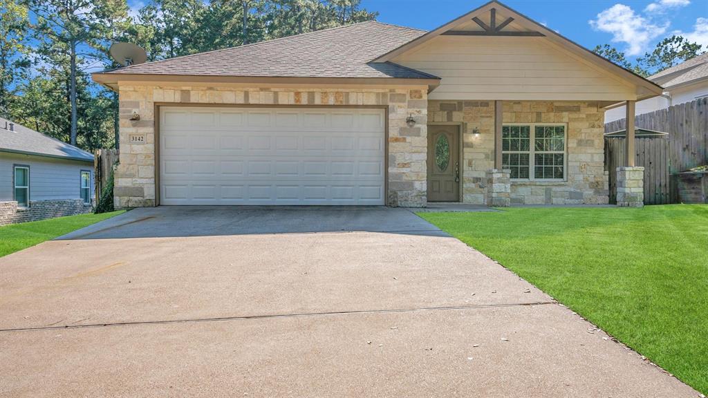 This single-story home features an attractive design with a stone facade, a gable roof with wooden accent, and a covered entrance.