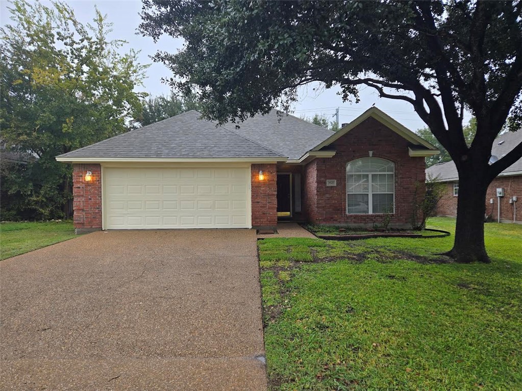 a view of a house with a small yard and a large tree