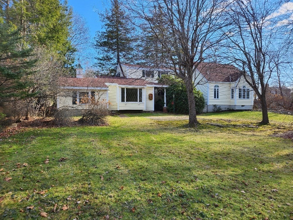 a front view of a house with a garden and trees