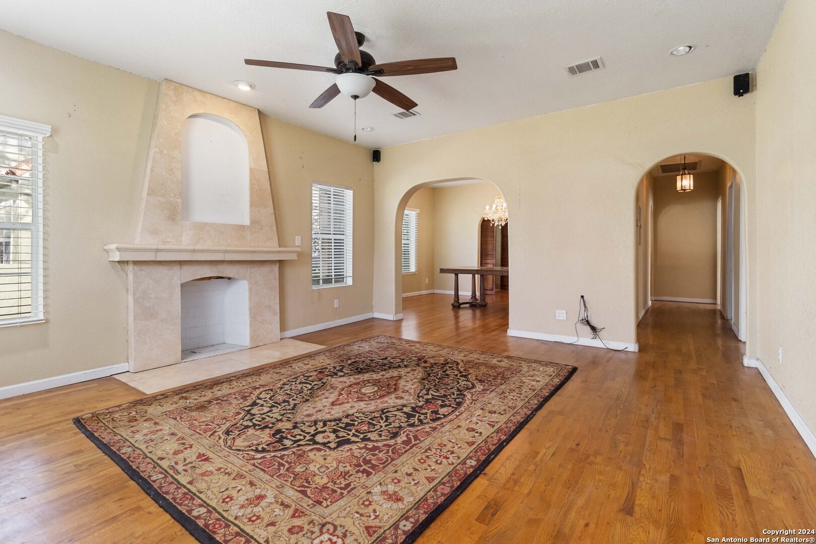 a view of a hallway with wooden floor and chandelier