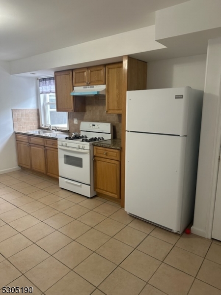 a white refrigerator freezer and a stove sitting inside of a kitchen