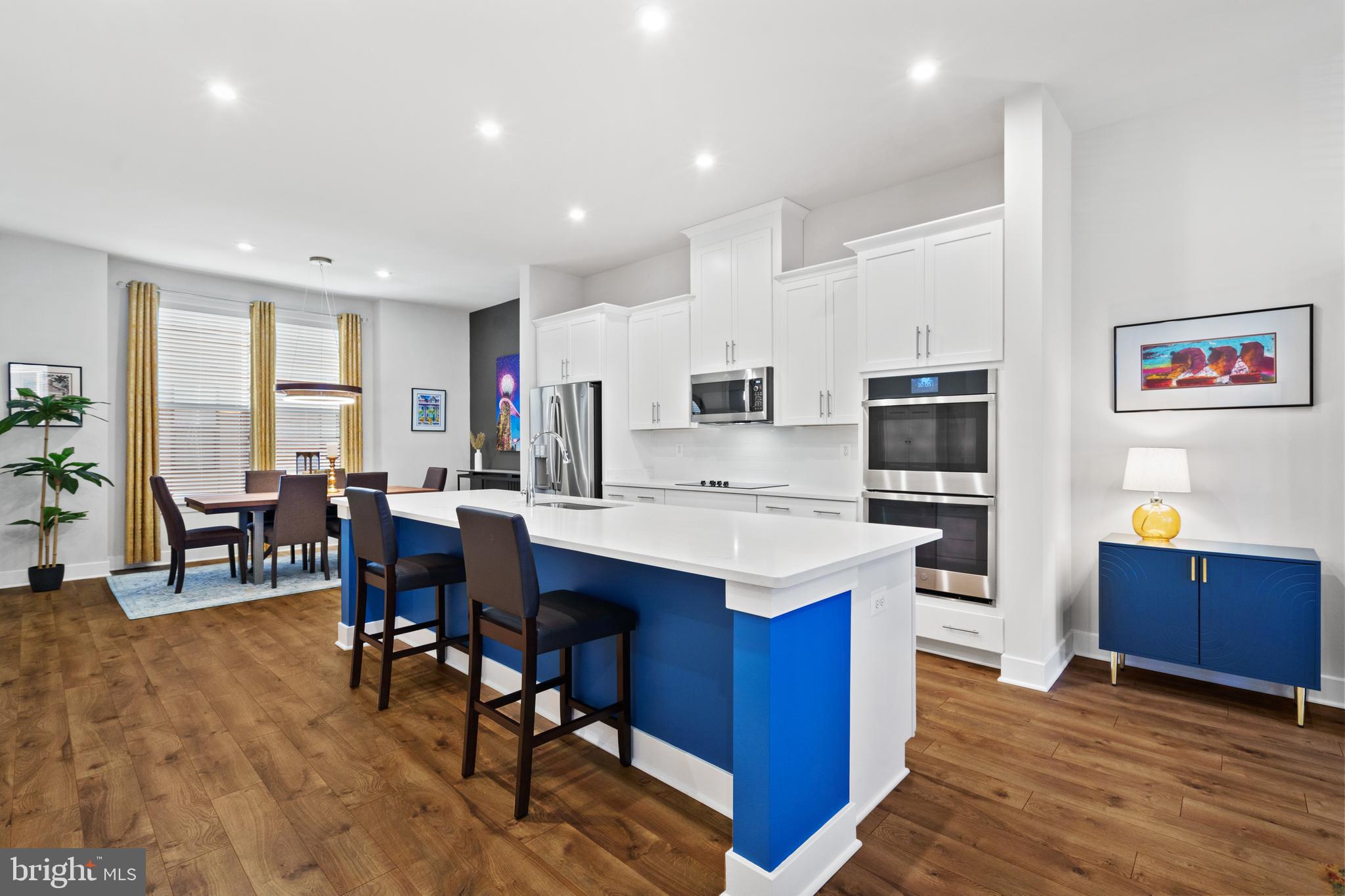 a kitchen with stainless steel appliances kitchen island granite countertop a table chairs and a refrigerator