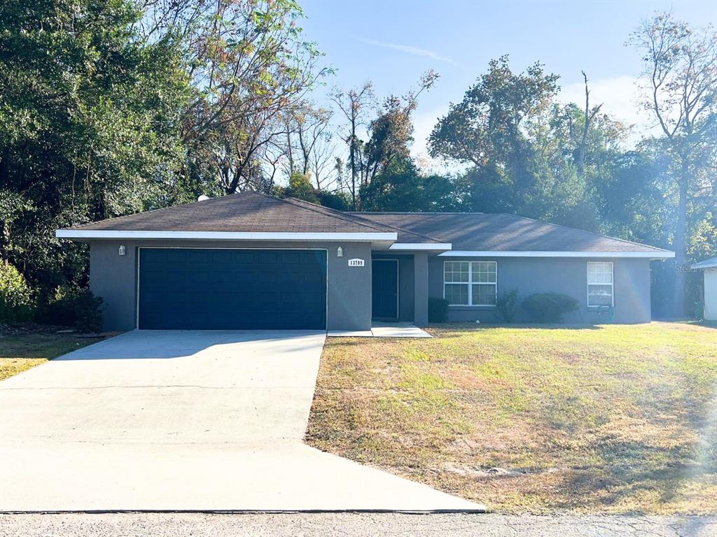 a front view of house with yard and trees in the background