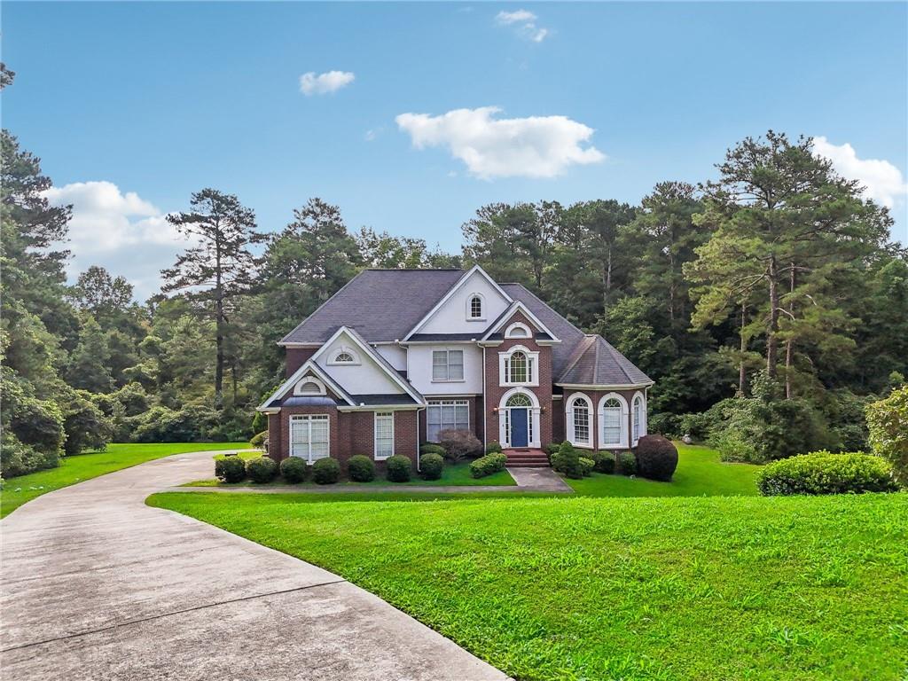 a view of a big house with a big yard and large trees