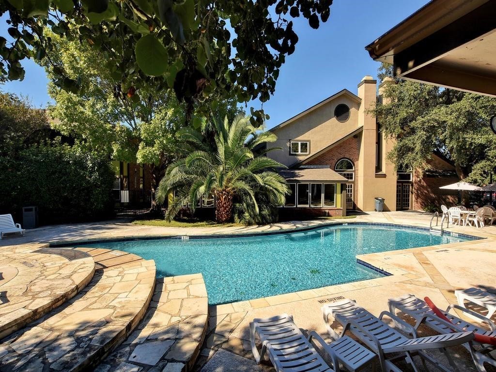 a view of swimming pool with lawn chairs and plants