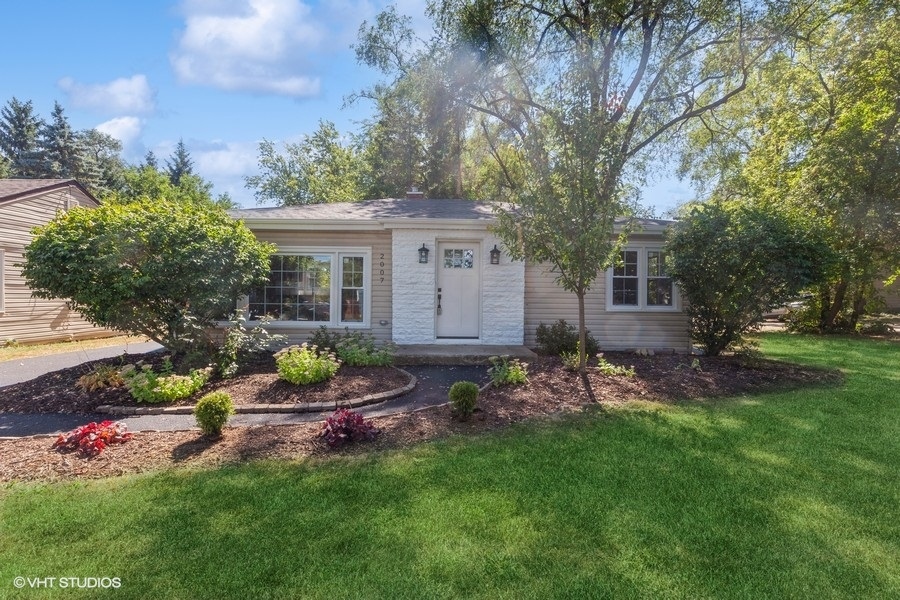 a backyard of a house with table and chairs plants and large tree