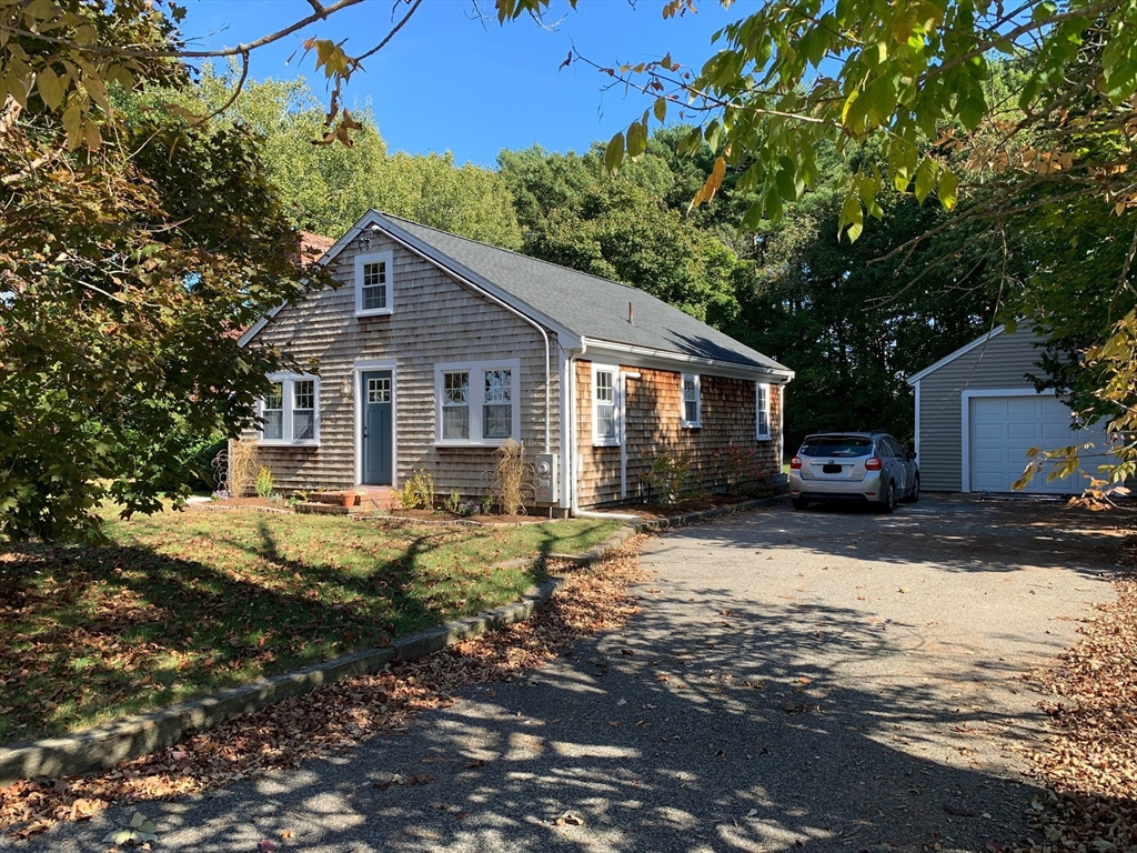 a front view of a house with a dirt yard and a large tree