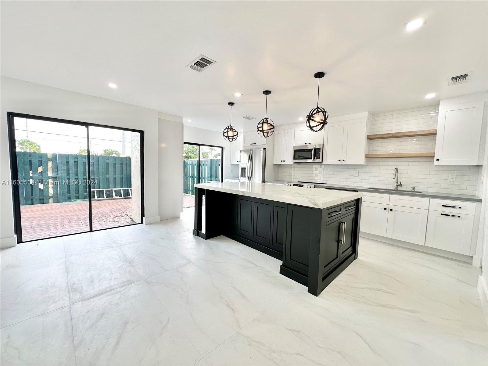 a large white kitchen with a large window and white cabinets