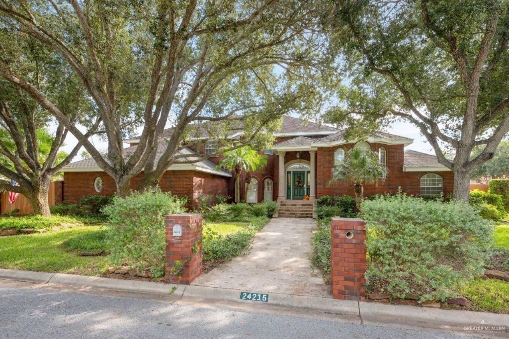 a front view of a house with a yard and tree s