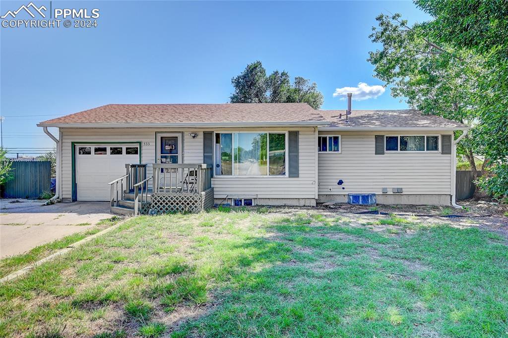 Single story home with a garage and a front lawn