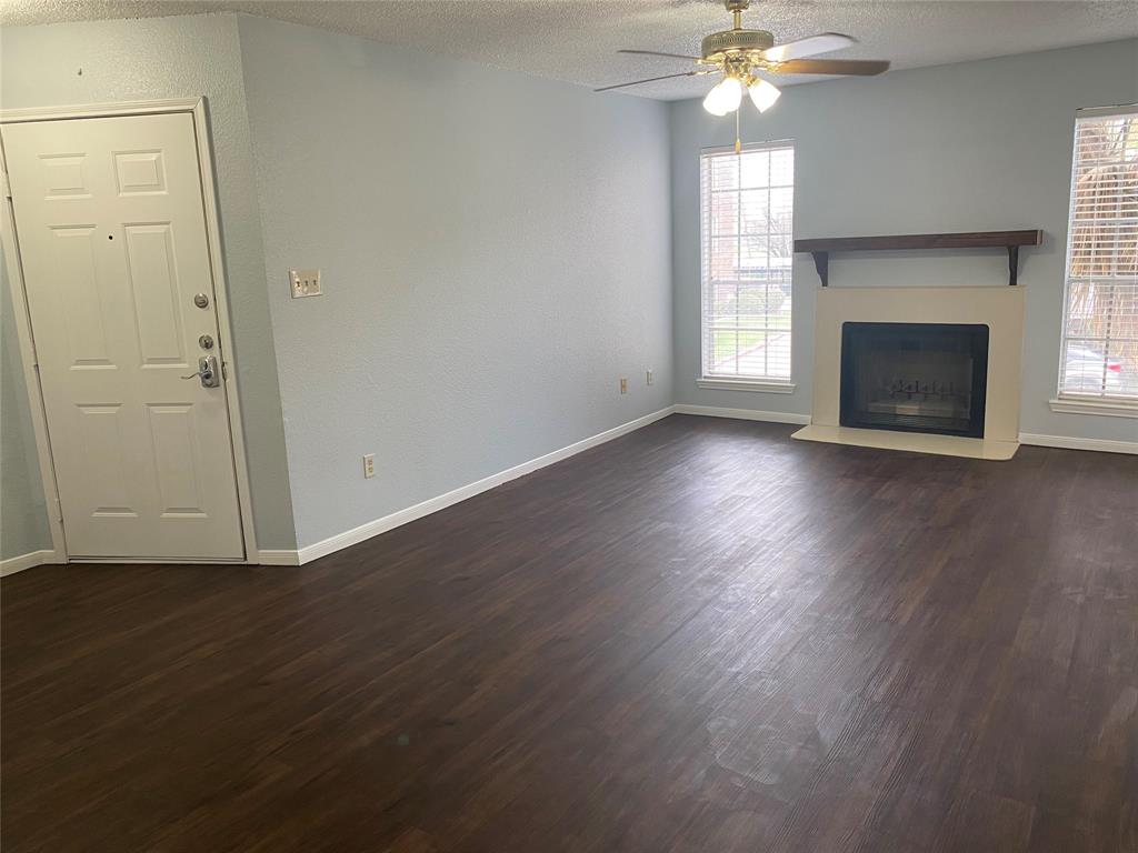 an empty room with wooden floor a chandelier fan and a fireplace