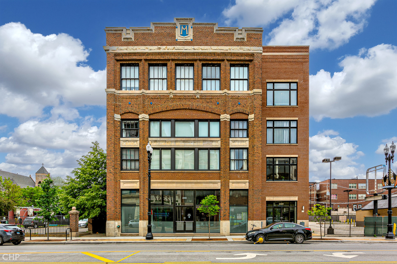 a front view of a building with lot of cars and trees