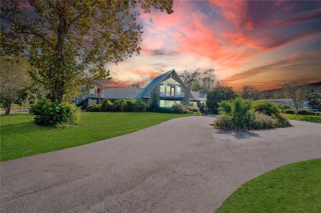 a view of a house with a big yard plants and large trees