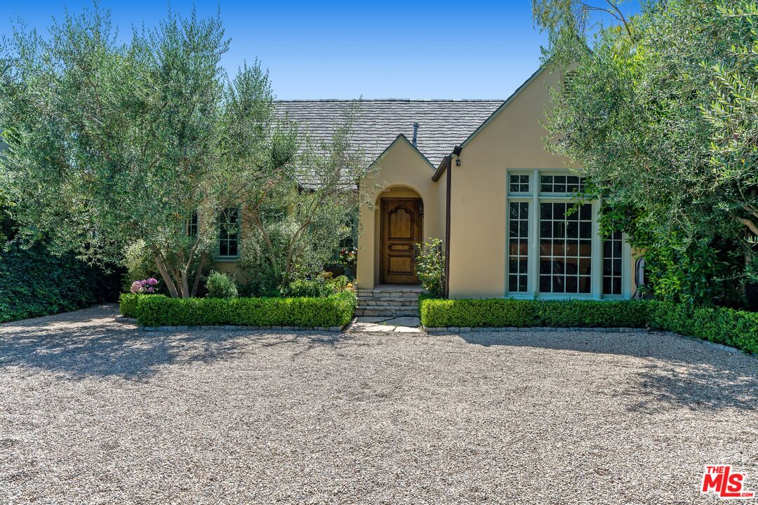 a view of a brick house with a yard and large trees