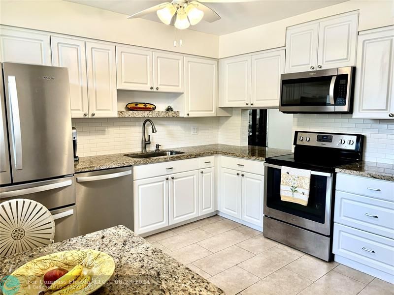 a kitchen with a refrigerator stove and white cabinets