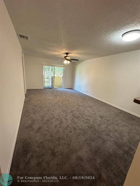 a view of a room with a ceiling fan and window